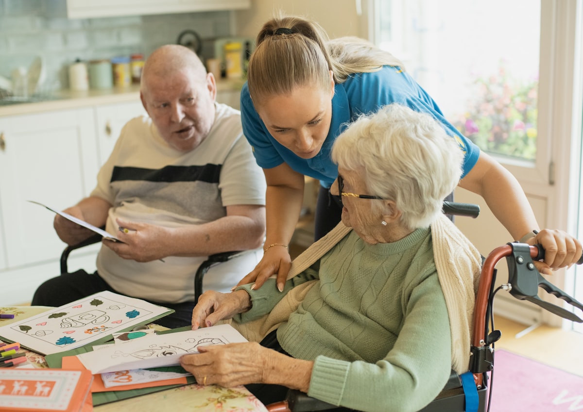 A caregiver assisting an elderly couple at a table