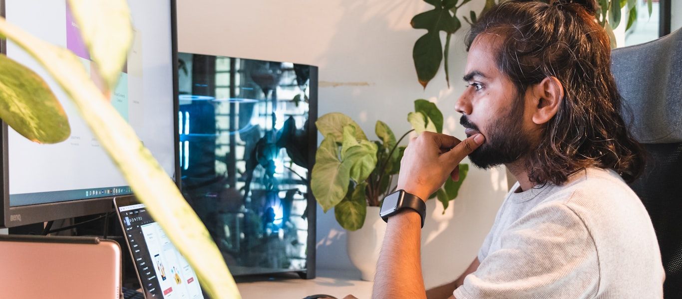 A software engineer focused at a workstation, reviewing an application on screen