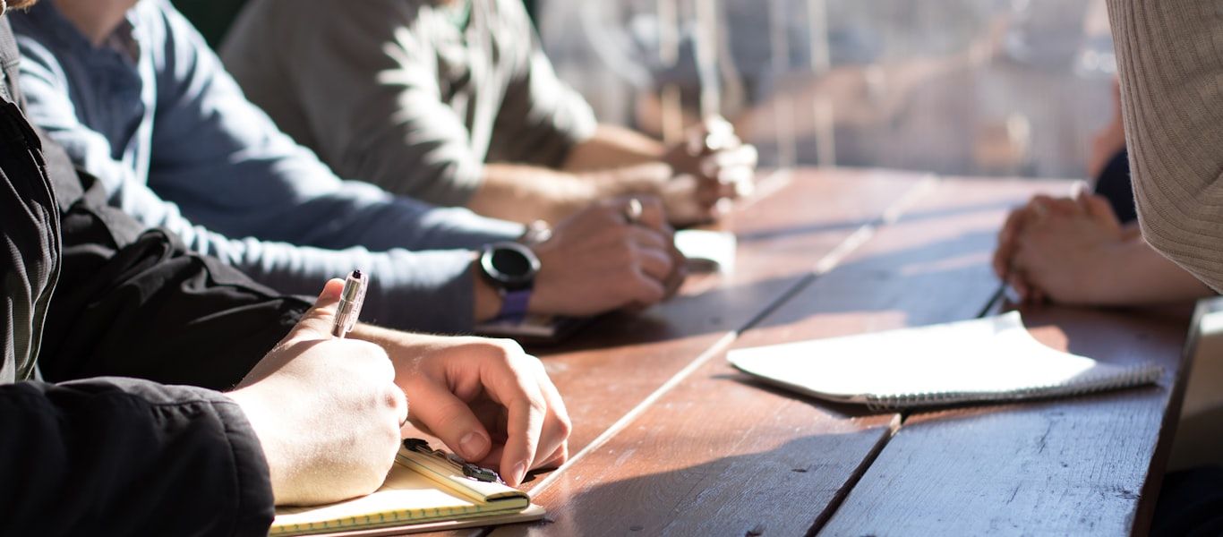Team members taking notes and reviewing documents together around a table